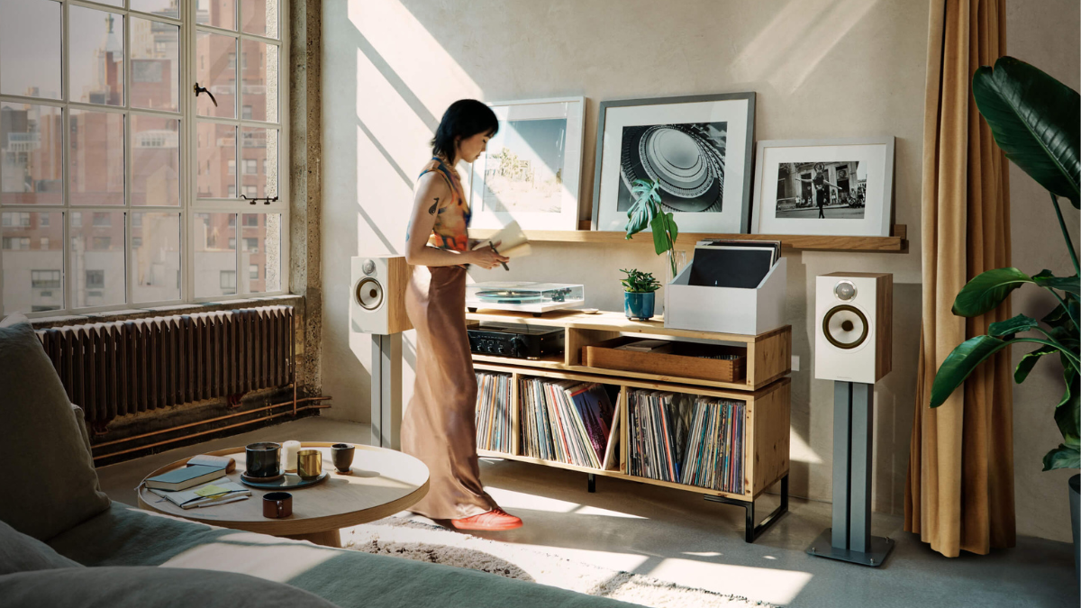 Person playing vinyl with bowers & Wilkins 606 S3 Speaker and turntable